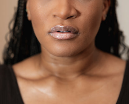 Close-up of a woman's face with a focus on her lips wearing a Luvelie metallic lip color.