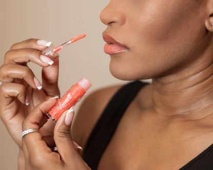 Woman holding a lip gloss with a beige background
